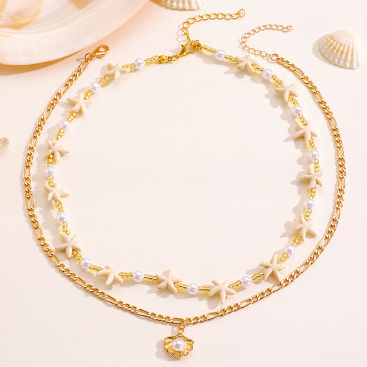 Gold-tone shell and pearl-style layered necklaces on a pale background